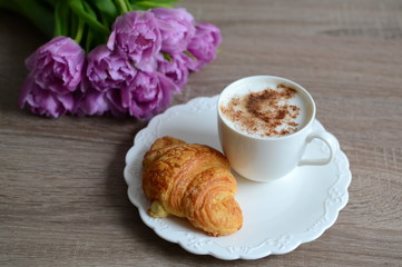 cup of cuppuccino and yummy croissant with flowers