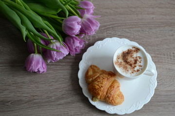 cup of cuppuccino and yummy croissant with flowers