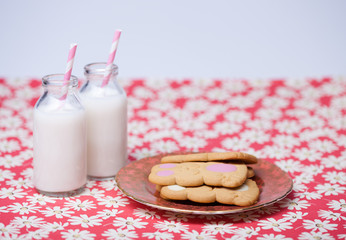 Milk and cookies. Plate of bunny shaped cookies and two mini bottles of milk with pink and white striped straws.