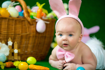 Fototapeta na wymiar Portrait of a cute funny baby dressed in Easter bunny ears with eggs