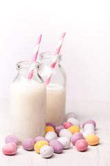 chocolate easter eggs and milkTwo mini milk bottles with straws and chocolate mini eggs scattered around the milk bottles.