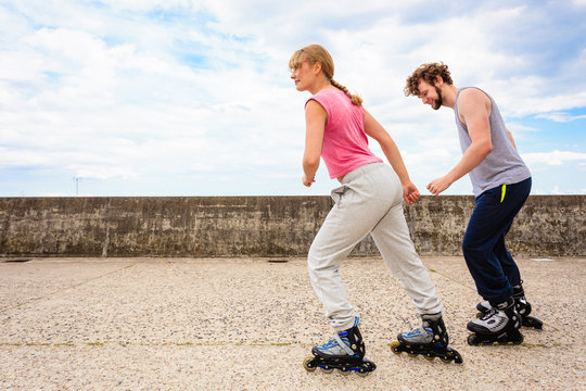 Two people race together riding rollerblades.
