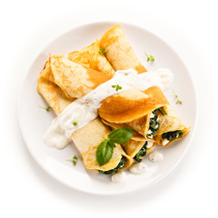 Crepes with spinach and feta cheese on white background 