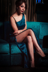 Naklejka premium girl in a blue evening dress sitting on a sofa