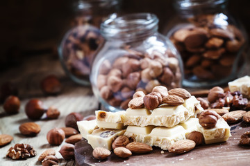 Delicious white chocolate, almonds, hazelnuts, on the old wooden