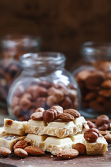 Delicious white chocolate, almonds, hazelnuts, on the old wooden