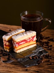 Two slices of sweet dessert on black stone with coffee