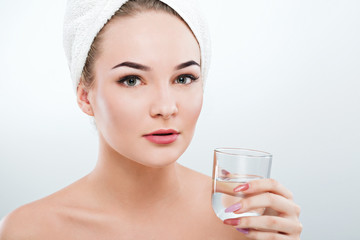 Girl with naked shoulders and white towel holding glass of water