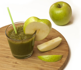 Glass of apple smoothie with drinking straw, on cutting board