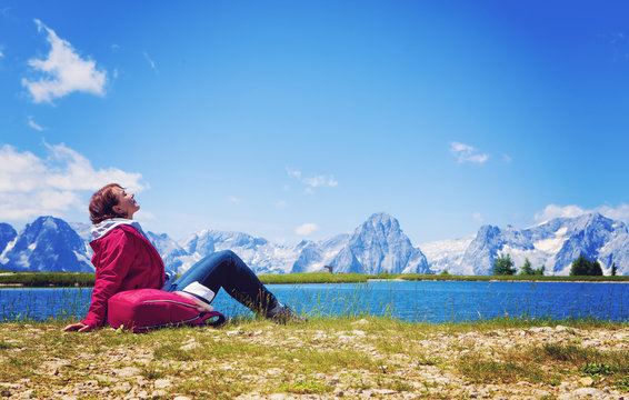woman sitting beside a clear mountain breathing the air