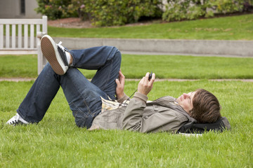 Male college student listening to digital music audio player on university campus