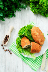 Ukrainian national dish , chicken Kiev  , cutlets of chicken meat in breadcrumbs with butter , dill, pepper and lettuce on a wooden background