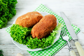 Ukrainian national dish , chicken Kiev  , cutlets of chicken meat in breadcrumbs with butter , dill, pepper and lettuce on a wooden background