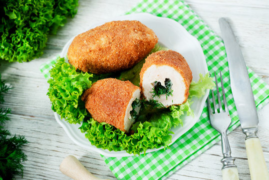 Ukrainian national dish , chicken Kiev  , cutlets of chicken meat in breadcrumbs with butter , dill, pepper and lettuce on a wooden background