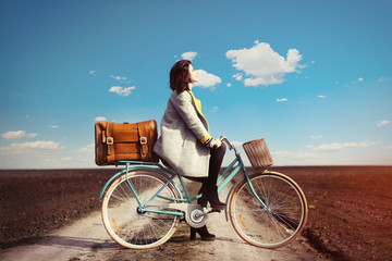 portrait of a young woman with a bicycle and suitcase