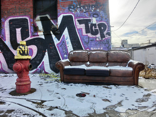 Abandoned couch in winter snow in urban setting - landscape color photo