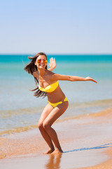 Naklejka premium brunette woman yellow bikini jump sea
