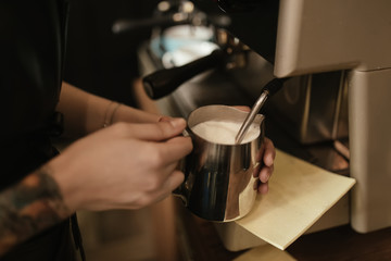 Fototapeta na wymiar Barista steaming milk at coffee machine