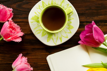 Breakfast. A cup of tea, flowers, notes on the wooden background
