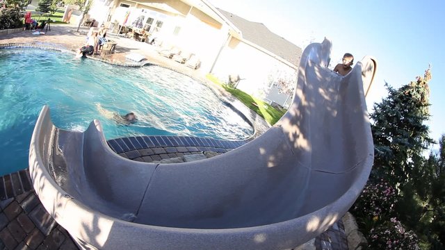 Kids going down water slide into pool