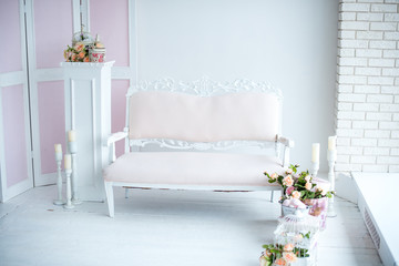 Interior design in white with old sofa and flowers and candles