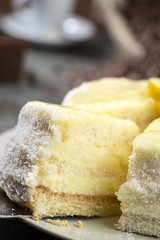 Lemon cake with coffee mug at the background close-up.