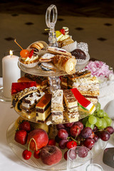 Assorted cakes, cookies and fruits on glass cake stand