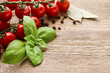 Tomatoes and basil leaves on wooden table