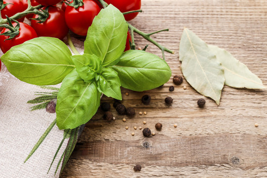 Tomatoes and basil leaves on wooden table