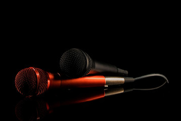 Two microphones lying on black surface. Black background, close up - obrazy, fototapety, plakaty