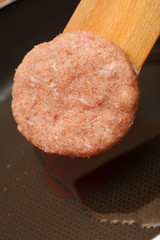 Fresh juicy patty of raw ground beef on a wooden board closeup
