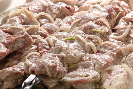 Marinated shashlik, meat grilling on metal skewer, close up.