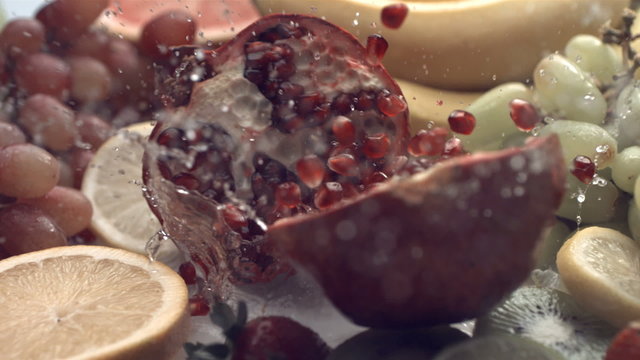 Pomegranate splashing into water, slow motion