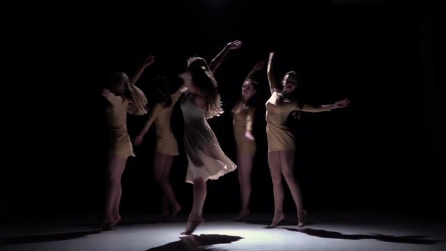 Five beautiful girls start dancing modern contemporary dance, on black, shadow, slow motion