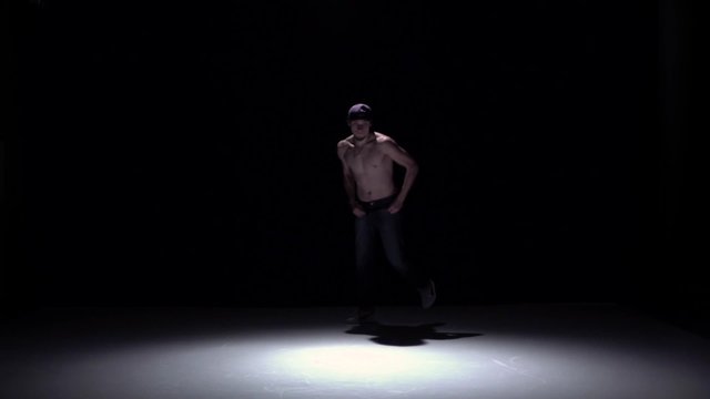 Talanted dancer man with naked torso dancing breakdance on black, shadow, slow motion