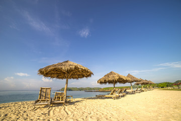A row of wooden lounge with direct sunlight at Lombok beach, Indonesia