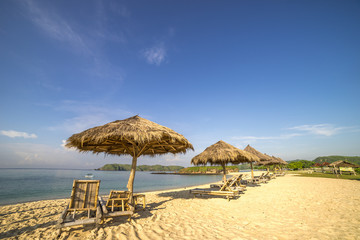 A row of wooden lounge with direct sunlight at Lombok beach, Indonesia