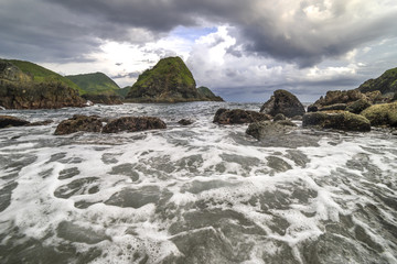 Obraz premium Natural rock with strong water wave and cloudy sunset background at Pantai Semeti Lombok, Indonesia.