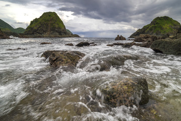 Natural rock with strong water wave and cloudy sunset background at Pantai Semeti Lombok, Indonesia.