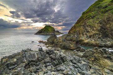 Naklejka premium Natural rock with strong water wave and cloudy sunset background at Pantai Semeti Lombok, Indonesia.