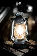 Vintage fashioned rustic kerosene oil lantern lamp burning with a soft glow light in an antique country barn