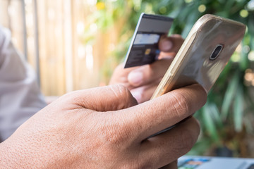 Closeup man's hands holding a credit card and using smartphone f