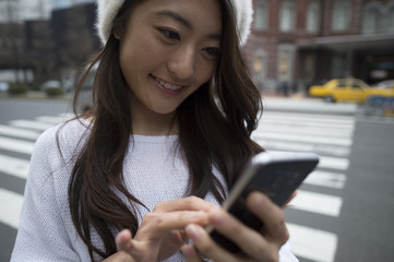 Young woman is looking at the smartphone in the city