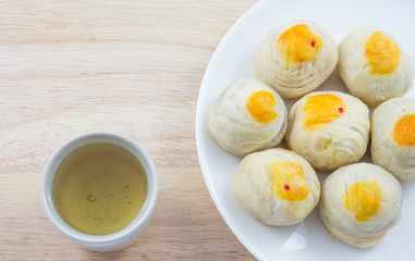 Chinese Pastry Mung Bean or Mooncake with Egg Yolk on dish wooden table and green tea cup