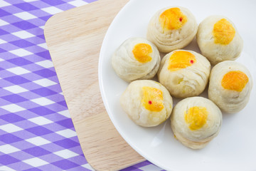 Chinese Pastry Mung Bean or Mooncake with Egg Yolk on dish and wooden table striped cloth