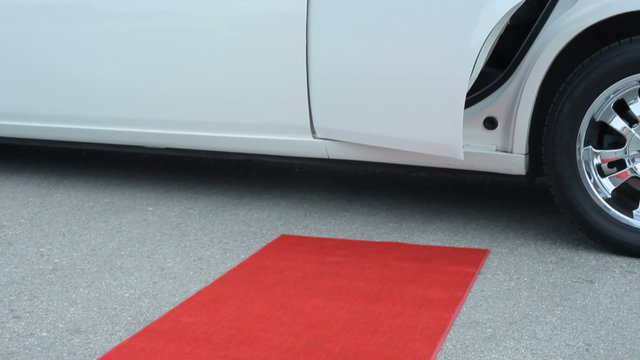 Businessman steps out of limo onto red carpet