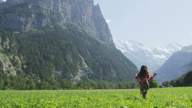 Happy woman having fun running in field nature excited of joy happiness. Joyful active lifestyle with free girl enjoying freedom, Lauterbrunnen valley, Swiss Alps, Switzerland. RED EPIC REAL TIME.