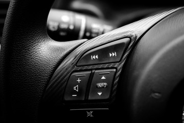 Close up of steering wheel of modern car. Volume and telephone command with cockpit background , black and white