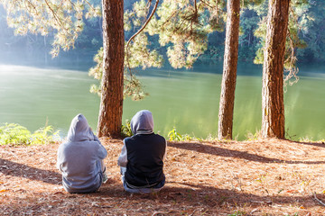 Couple relaxing with worm sunlight in the cold morning near lake