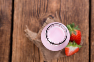 Milk (Strawberry flavoured) on wooden background